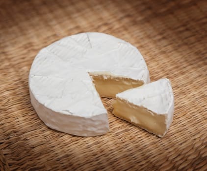 Fresh slice of Camembert cheese natural, on a straw Mat
