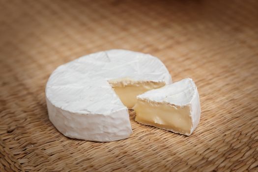 Fresh slice of Camembert cheese natural, on a straw Mat