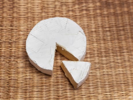 Fresh slice of Camembert cheese natural, on a straw Mat