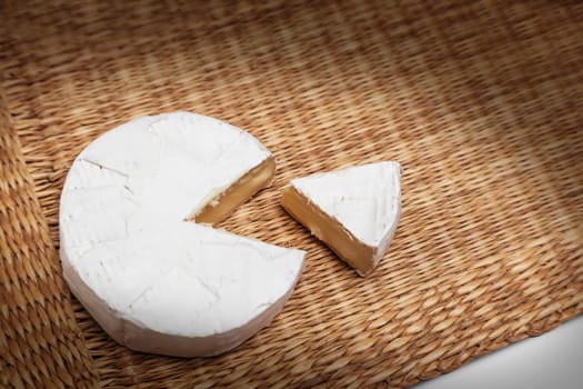 Fresh slice of Camembert cheese natural, on a straw Mat