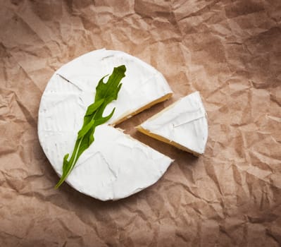 Fresh slice Camembert cheese natural, on Kraft paper brown background. With clipping path