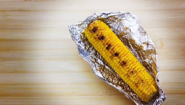 Tasty grilled corn on brown wooden table