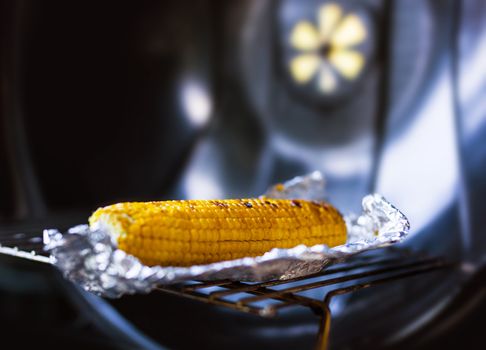 Baked yellow corn in foil on the grill
