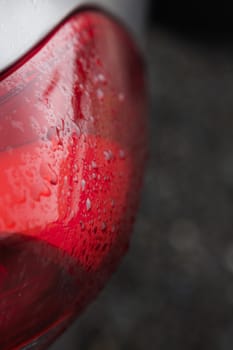 Raindrops on a red car headlight isolated background