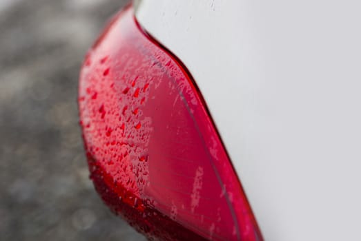 Raindrops on a red car headlight isolated background