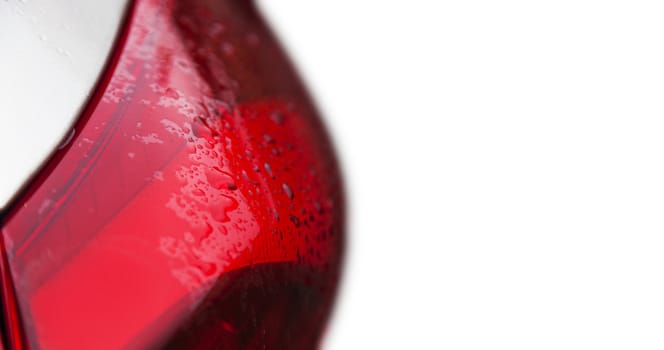 Raindrops on a red car headlight isolated background