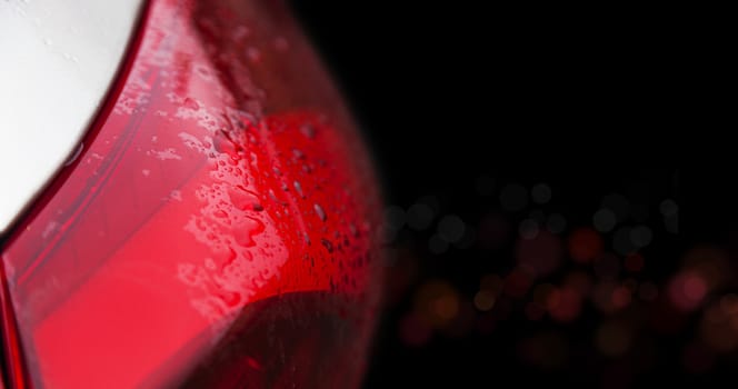 Raindrops on a red car headlight isolated background