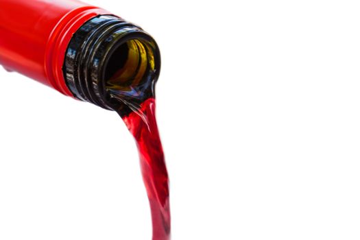 Pouring red wine from bottle into the wineglass on white background. Blurred concept