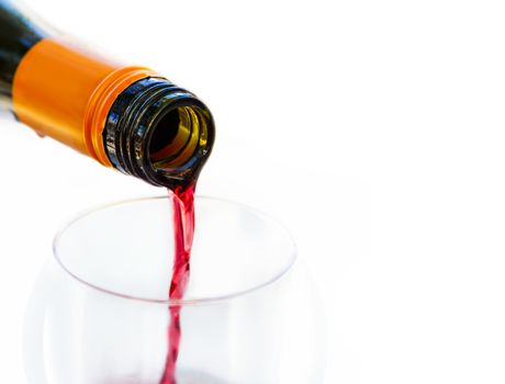 Pouring red wine from bottle into the wineglass on white background. Blurred concept