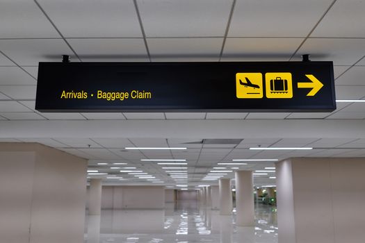 Arrivals baggage claim information board sign with yellow character on black background at international airport terminal.