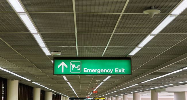 Emergency exit information board sign with white character on green background at international airport terminal.