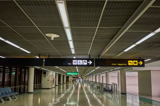 Toilets and arrivals baggage claim information board sign with yellow character on black background at international airport terminal.