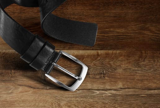 Black men's leather belt isolated on wood background. With clipping path.