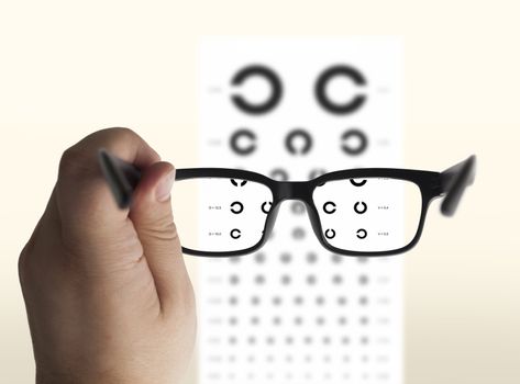 Eyeglasses in hand for eyesight. On the background of a chart test for eyes of Landolt C, isolated
