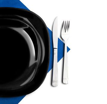 Black plate, fork and knife on blue napkin. Isolated on white.