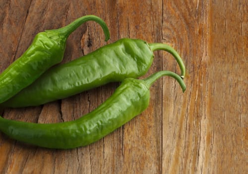 Green peppers on wood background