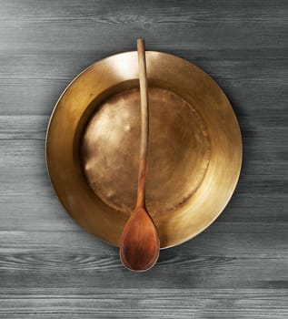 Empty copper tray, wooden spoon on a wooden table. With clipping path