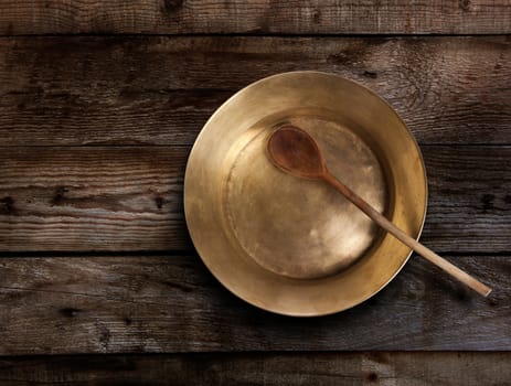 Empty copper tray, wooden spoon on a wooden table. With clipping path