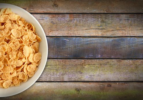 Corn flakes in a plate on a wooden table. View from the top