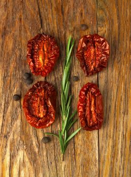 Delicious Dried Tomatoes, a branch of rosemary in a Rustic style, on wood background