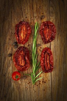 Delicious Dried Tomatoes, a branch of rosemary in a Rustic style, on wood background