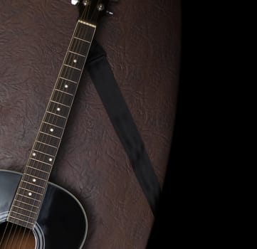 Black acoustic guitar on a background of brown leather