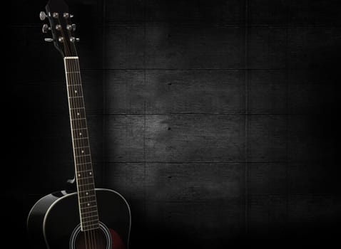 Black acoustic guitar on dark black wooden background.