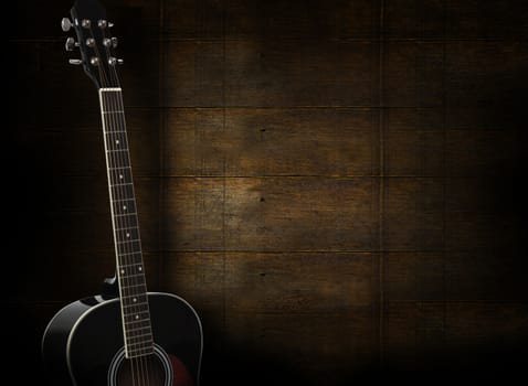 Black acoustic guitar on dark yellow wooden background.
