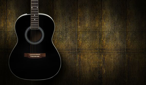 Black acoustic guitar on dark yello wooden background.