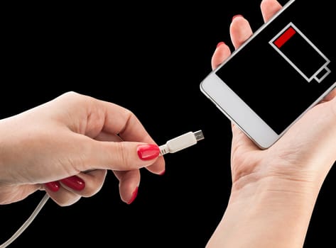 Female hand holding low battery smartphone and connect charger isolated on black background