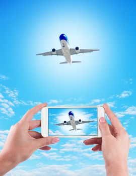 Female Hand holding using mobile phone and airplane on a blue background