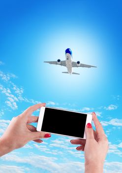 Female Hand holding using mobile phone and airplane on a blue background