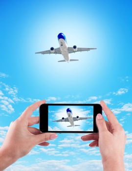 Female Hand holding using mobile phone and airplane on a blue background