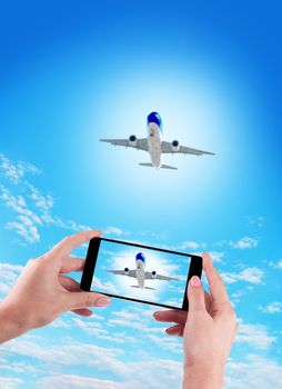 Female Hand holding using mobile phone and airplane on a blue background