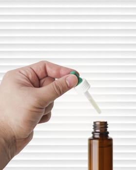 Hand man scientist, doctor keeps the pipette for drop over the container with liquid, medication or chemical substance laboratory. Isolated on white of stripes background with clipping path