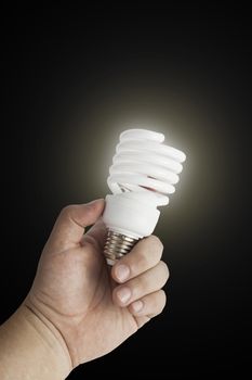 Energy saving lamp in the man's hand on black background closeup. With clipping path