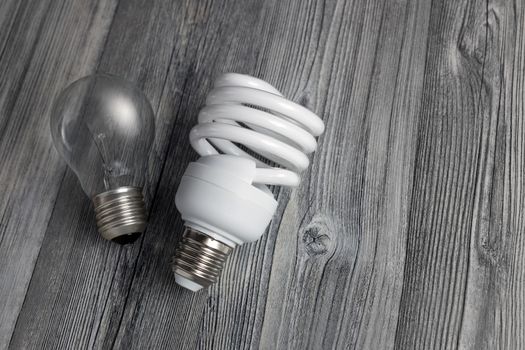 Energy-saving lamp and incandescent bulb on wooden background. Sales of light bulbs. Advertising on lighting technology.