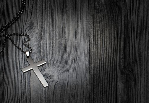 Metal cross on a wooden background