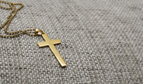 Gold metal cross on a background of rough cloth