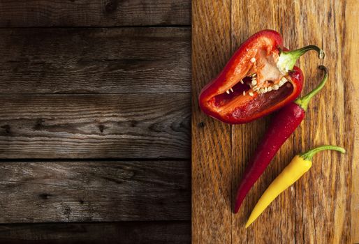 Red pepper slice and colorful chili peppers on a wooden background old panel.