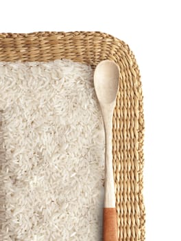 Asian uncooked white rice in a wooden spoon on a background of straw.