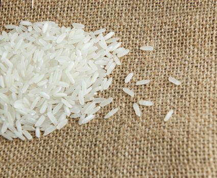 Asian uncooked white rice on a background of rough cloth