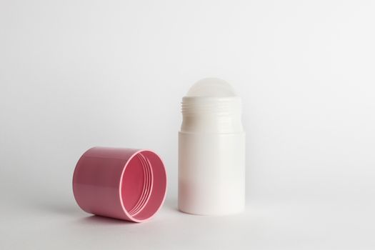 Roll-on antiperspirant cosmetic and pink cover isolated on white background