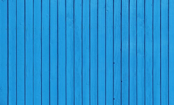 Wooden slat fence with parallel planks with blue paint.