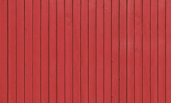 Wooden slat fence with parallel planks with red paint.