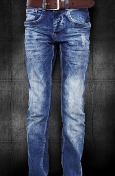 Blue jeans for the teenager with a belt. On a dark black background wood texture. With clipping path