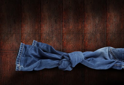 Jeans knot on dark brown wooden background. With clipping path