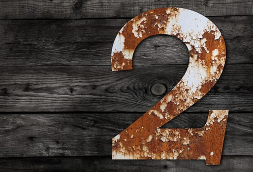 Old rusty metal alphabet, text 2 on Wooden Background nails.