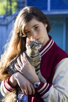 Autumn sunny photo of a teenage girl hugging her cat, close-up, outdoor photo on a blue background