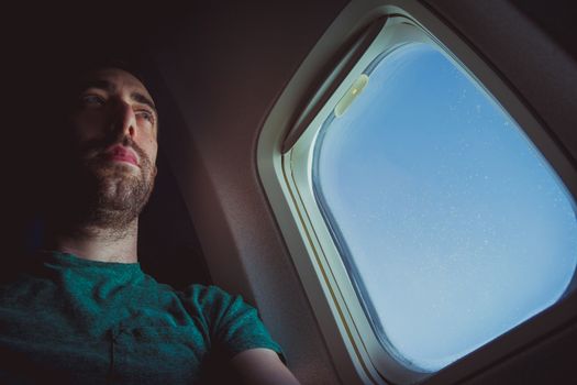 Pensive man seat by the window of an airplane.